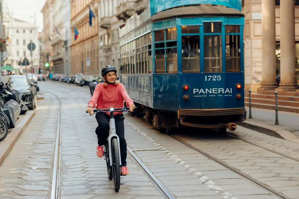 Cycliste sur un Stromer ST2 blanc, sur une rue pavée avec un tramway