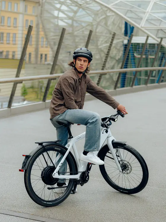 Cycliste assis sur un Stromer ST3 blanc, sur une passerelle